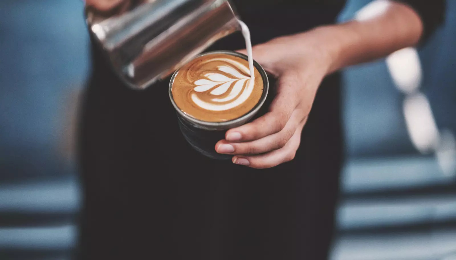 Barista pouring milk on coffee cup